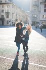 Two female friends walking and laughing in town square — Stock Photo