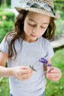 Girl examining flower outdoors — Stock Photo