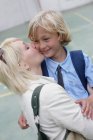Школьный мальчик целуется с матерью — стоковое фото