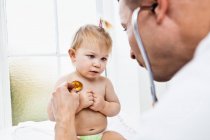 Doctor examining toddler girl with stethoscope — Stock Photo