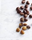 Fresh chestnuts on marble table — Stock Photo