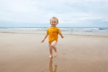 Мальчик ходит волнами по пляжу — стоковое фото