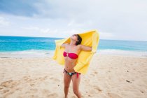 Mujer sosteniendo toalla amarilla en la playa, St Maarten, Países Bajos - foto de stock