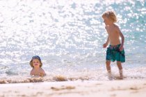 Дети играют в волны на пляже — стоковое фото