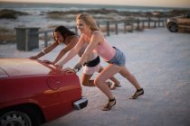Girls pushing their broken car — Stock Photo