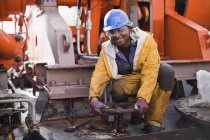 Worker turning wheel on oil rig — Stock Photo