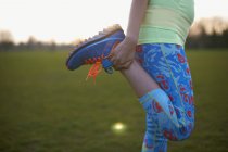 Обрізане зображення жінки, що розтягує ногу для вправ у парку — стокове фото