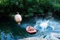 Hombres saltando en el lago del bosque - foto de stock