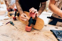 Men in workshop attaching wheels to skateboards — Stock Photo