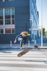 Молодий чоловік міський скейтбордист робить стрибок у скейтборді на пішохідному переході — стокове фото