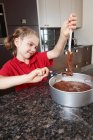 Menina derramando mistura de bolo em lata de bolo — Fotografia de Stock