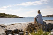 Woman sitting and looking out to sea — Stock Photo