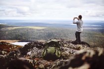 Caminante tomando fotografías en la cima del acantilado, Keimiotunturi, Laponia, Finlandia - foto de stock