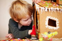 Boy decorating gingerbread house — Stock Photo