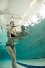 Женщина учит ребенка плавать в бассейне — стоковое фото