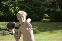 Мальчик в саду бросает мяч для регби — стоковое фото