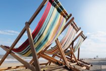 Tre sedie a sdraio vuote sulla spiaggia alla luce del sole, vista posteriore — Foto stock