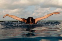 Девушка плавает в бесконечном бассейне — стоковое фото