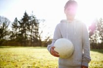 Мальчик несет футбольный мяч на лугу — стоковое фото