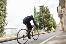 Person cycling up road near buildings — Stock Photo
