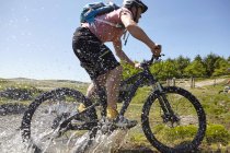 Ciclistas de bicicleta através da água — Fotografia de Stock