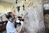 Скульптор вырезает фигурку из дерева — стоковое фото