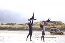 Батьки, які піднімають синів на пляжі — стокове фото