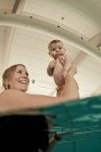 Donna che gioca con il bambino in piscina — Foto stock