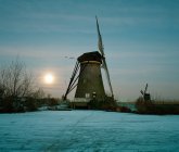 Rural windmill on frozen river — Stock Photo