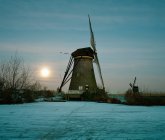 Moulin à vent rural sur rivière gelée — Photo de stock