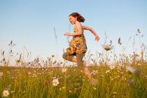 Menina correndo no campo das flores, foco seletivo — Fotografia de Stock