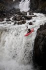 Чоловік катається на каное над скелястим водоспадом — стокове фото