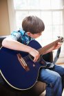 Menino tocando guitarra no sofá — Fotografia de Stock
