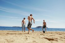 Uomini che giocano a calcio sulla spiaggia — Foto stock