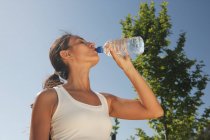 Mujer bebiendo agua al aire libre - foto de stock
