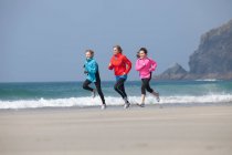 Family running together on beach — Stock Photo