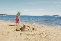 Child making moat around sandcastle — Stock Photo