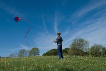 Хлопчик літає повітряним змієм у полі — стокове фото