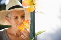 Ältere Frau riecht Blumen im Freien — Stockfoto