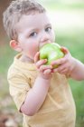 Хлопчик їсть яблуко на відкритому повітрі — стокове фото