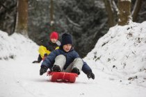 Children sledding on snowy slope — Stock Photo
