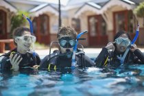 Tres jóvenes buceadores adultos entrenando en la piscina - foto de stock