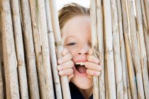 Menino sorrindo atrás da cerca, foco em primeiro plano — Fotografia de Stock