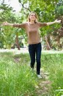 Женщина с поднятыми руками гуляет в парке — стоковое фото