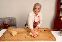 Older woman kneading dough on board — Stock Photo