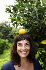Frau balanciert Mandarine auf dem Kopf — Stockfoto