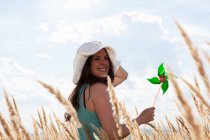 Mulher segurando pinwheel em wheatfield — Fotografia de Stock