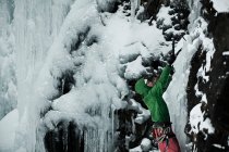 Escalador con picos que descienden colina nevada - foto de stock