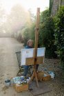 Artiste masculin mature peinture toile sur l'allée de la maison — Photo de stock