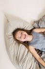 Вид улыбающейся девушки, лежащей на кровати — стоковое фото